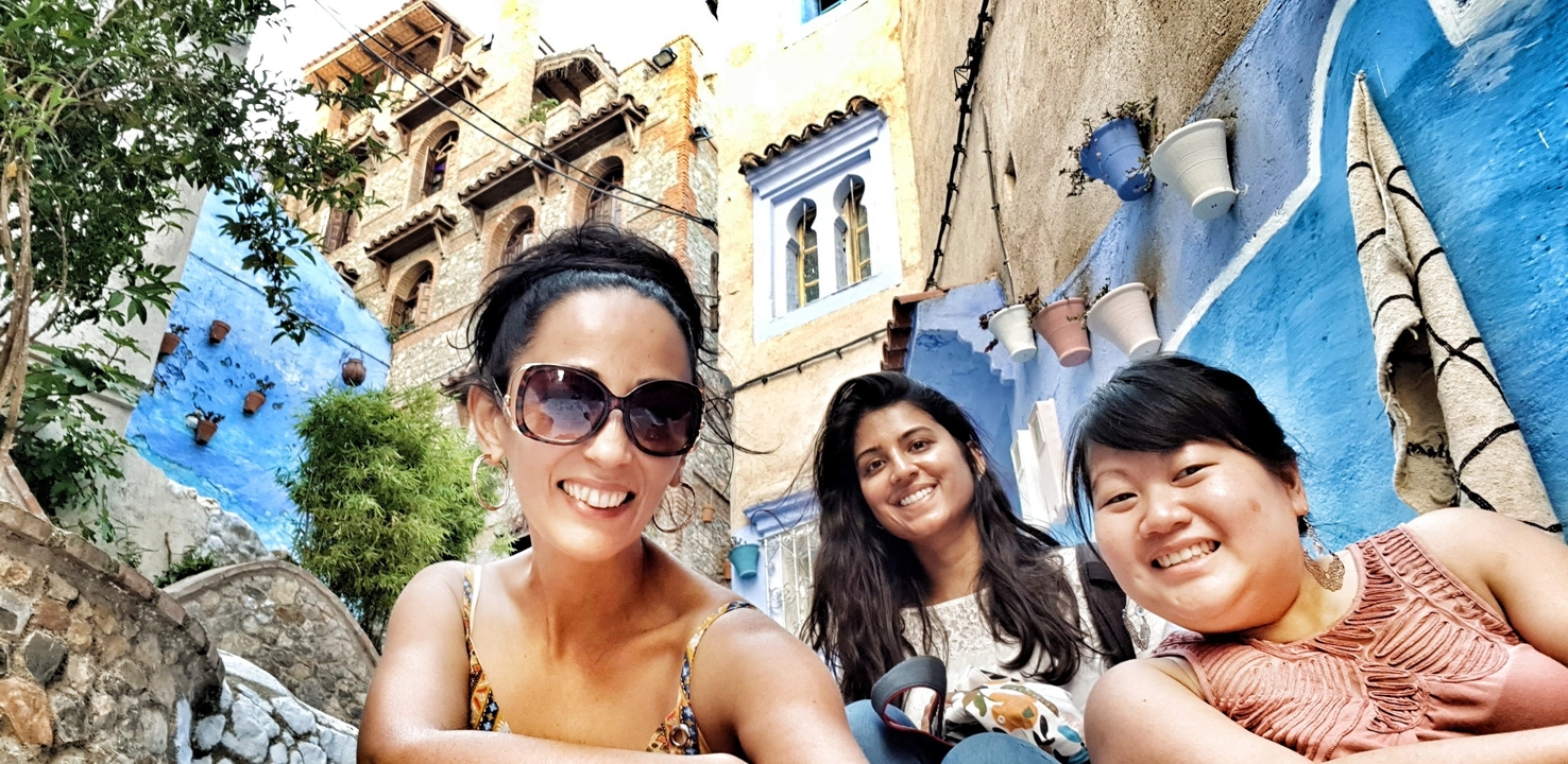 Three women posing in a colorful alleyway.