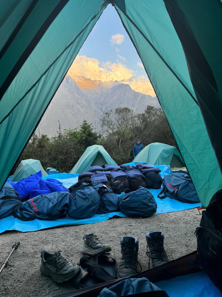 Camping setup with tents and supplies in the mountains.