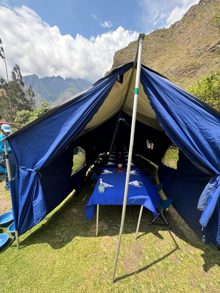 Dining tent set up with a long table covered by blue cloth.