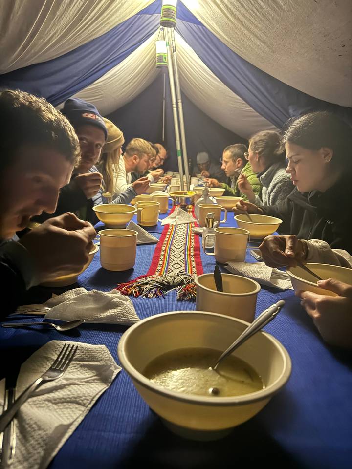 Group of people eating together at a long table with bowls.