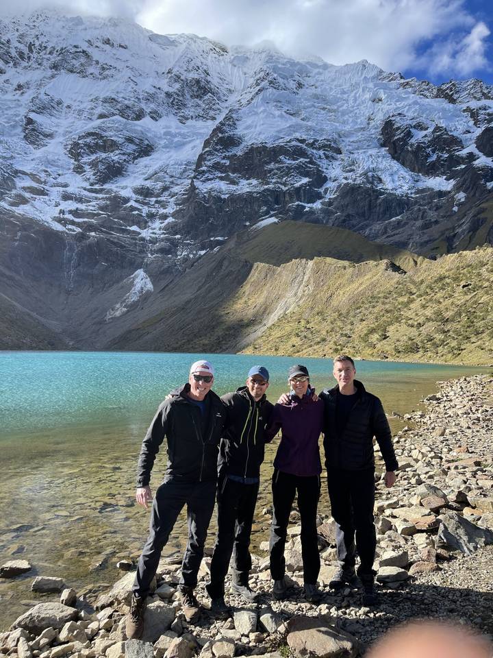 Hikers posing in front of a snowy mountain and lake.