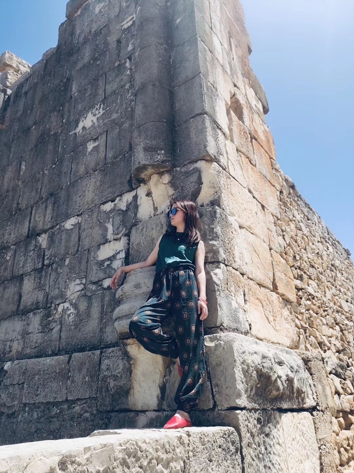 A person posing against an ancient stone structure.