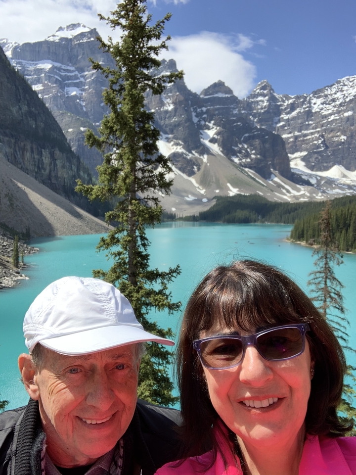 Vue panoramique sur le lac avec montagnes et arbres ; vue partielle de deux personnes.