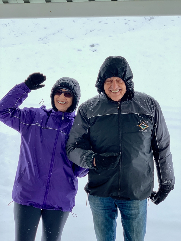 Deux personnes souriantes en vêtements d'hiver avec de la neige qui tombe.