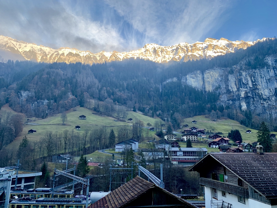 Village in front of mountains with snowy peaks.