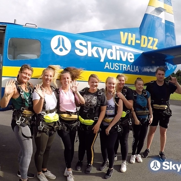 Group of skydivers posing in front of an airplane.