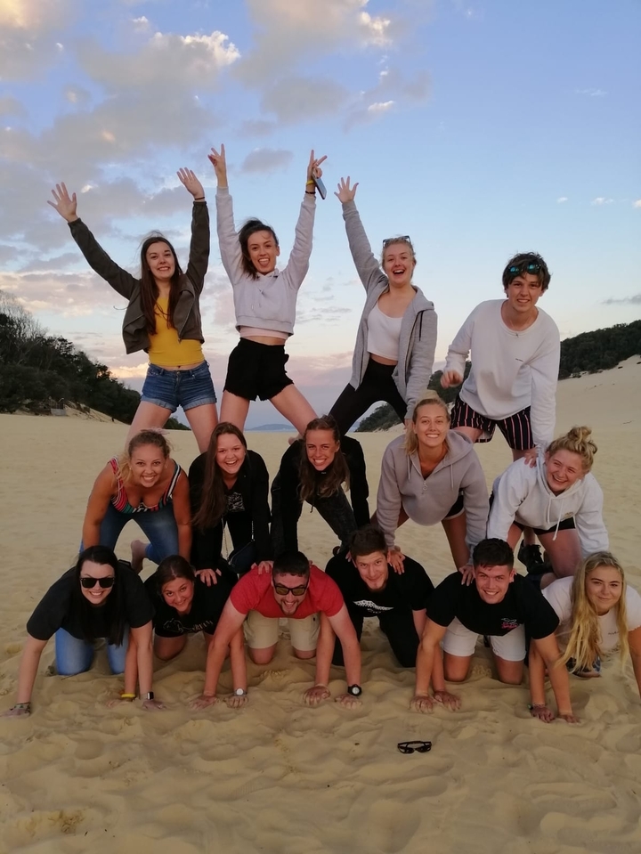 Group of friends forming a pyramid on the sand.