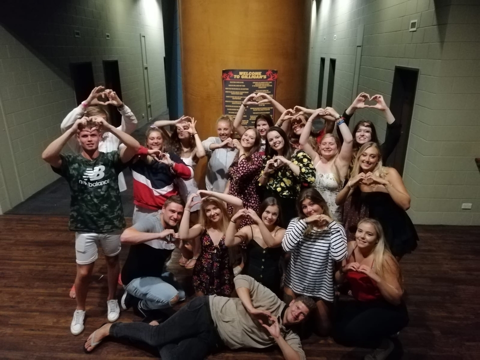 Group photo with heart hand gestures indoors.