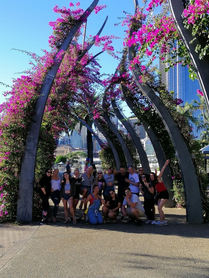Group photo under floral arches in a city park.