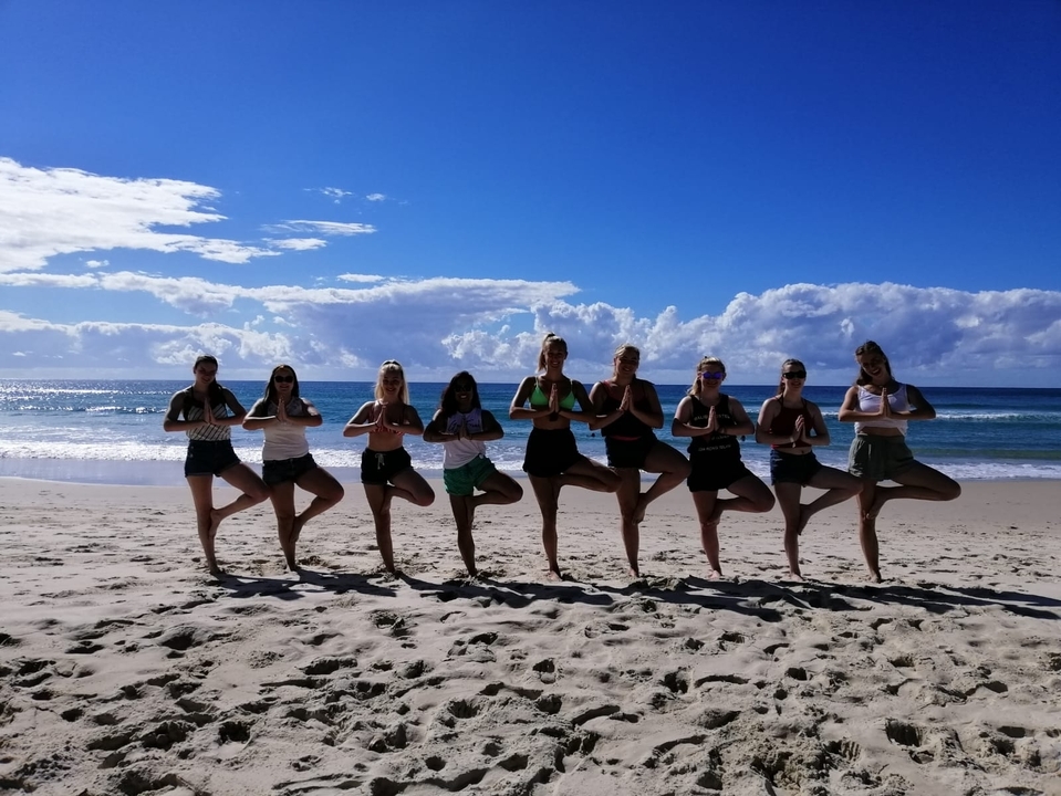 Group of people practicing yoga on a beach.