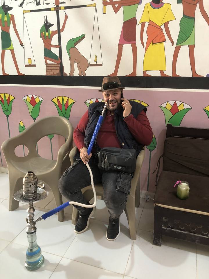 Une personne assise avec un narguilé à l'intérieur d'une pièce peinte.