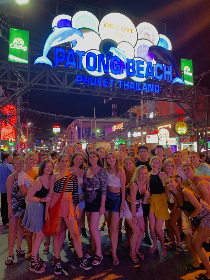 Large group posing in a colorful, busy street at night.