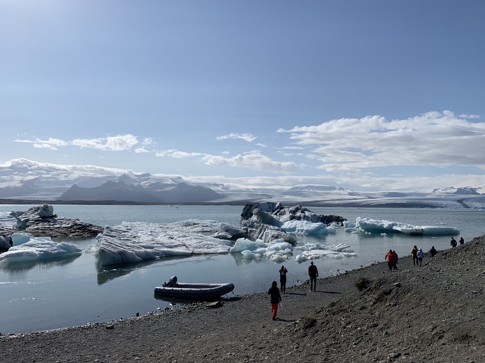 Icebergs floating in a glacial lagoon with mountains in the background under a cloudy sky.