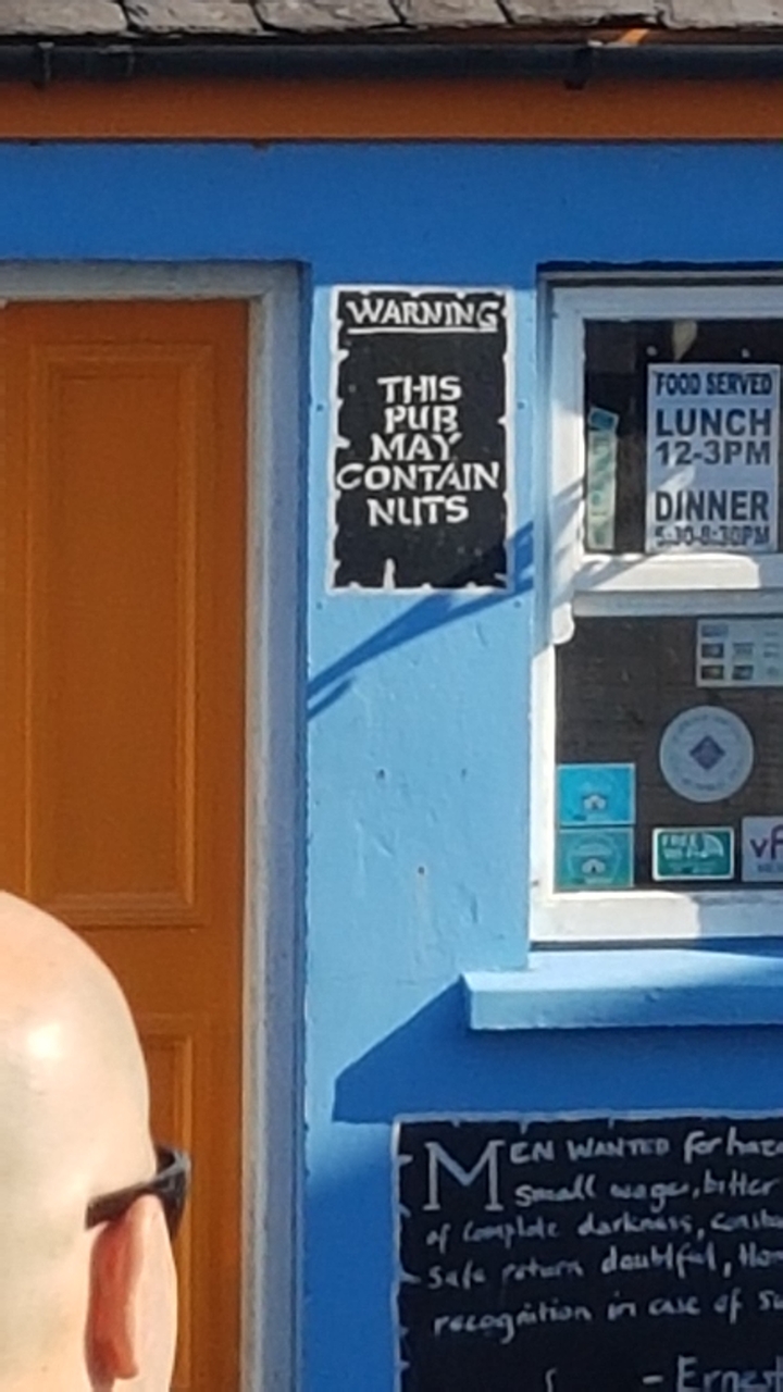 Close-up of a shop sign on a colorful wall.