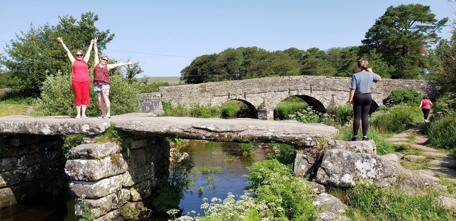 People posing on a stone bridge over a stream