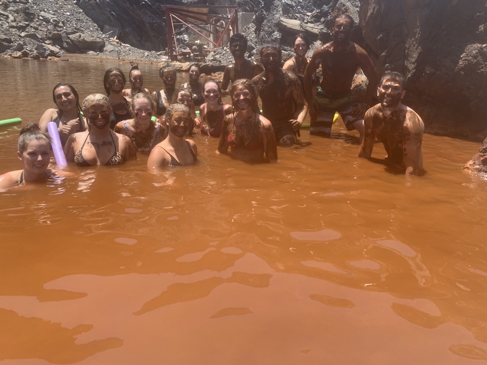Group of people covered in mud in a natural pool