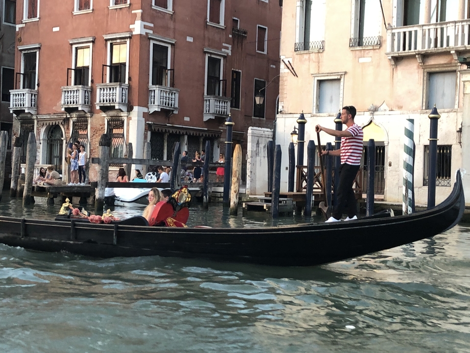 Gondolier steering a gondola with passengers on a canal.