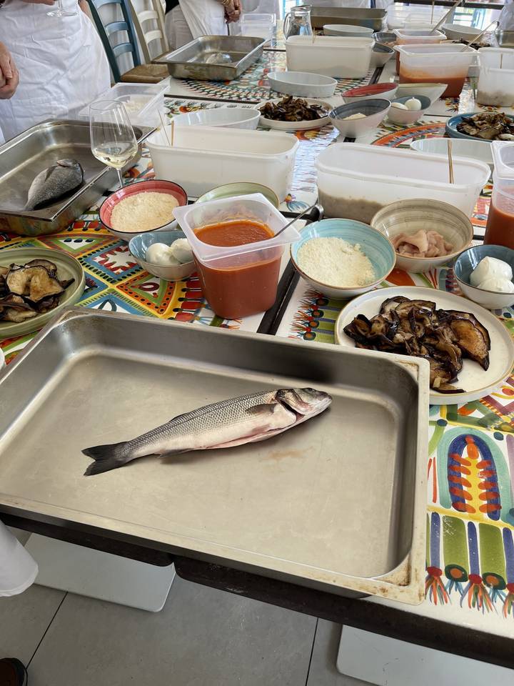 A fish on a tray surrounded by various ingredients and cooking preparations.