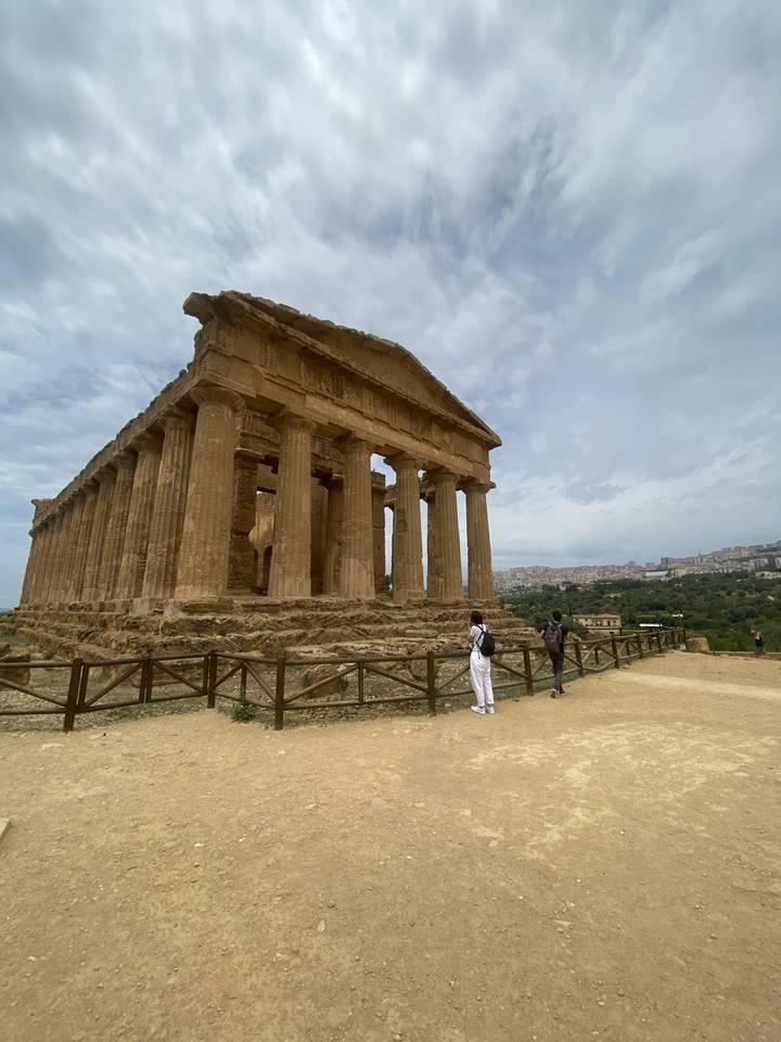Ancient temple with columns and visitors in the foreground.