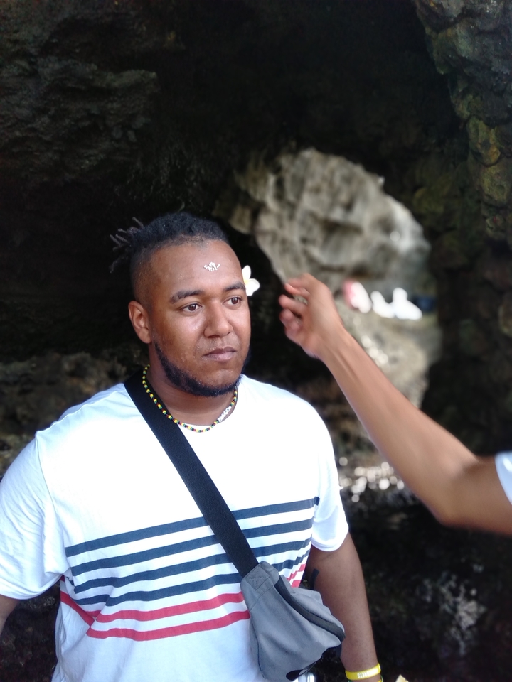 A man receiving a traditional mark on his forehead, with a rocky backdrop.