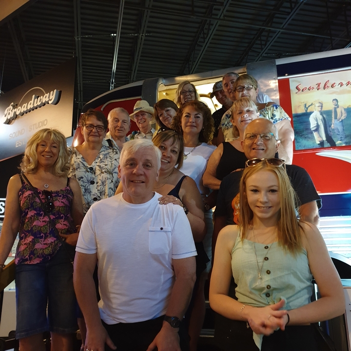 Groupe de personnes posant devant un véhicule au style rétro.