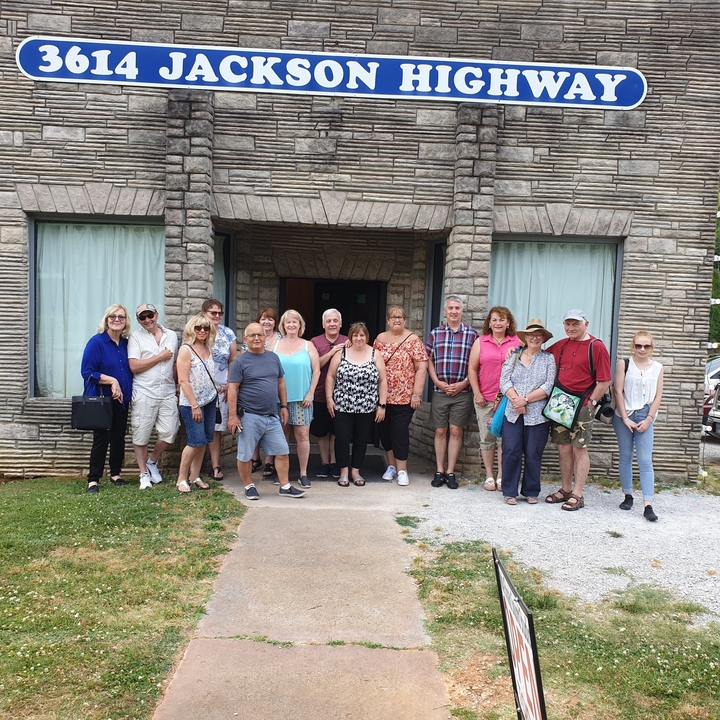 Groupe de personnes posant devant un bâtiment en pierre.