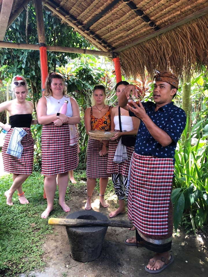Instructor showing items to a group of women in traditional attire.