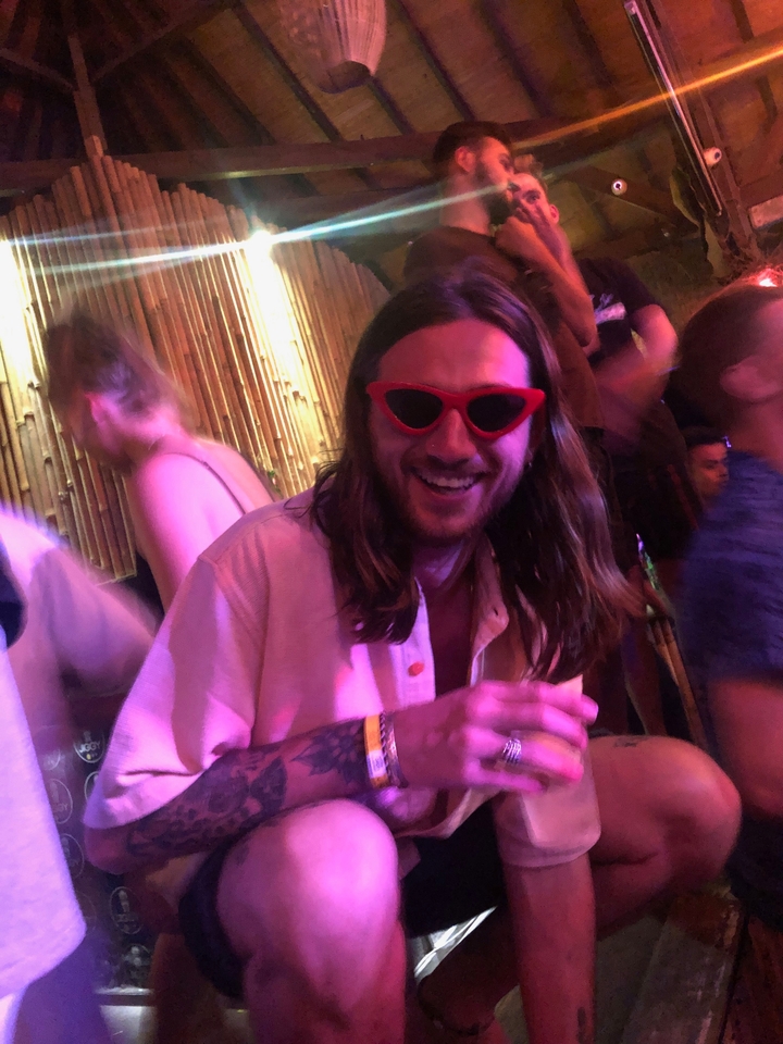 Close-up of a person at a party with red sunglasses.