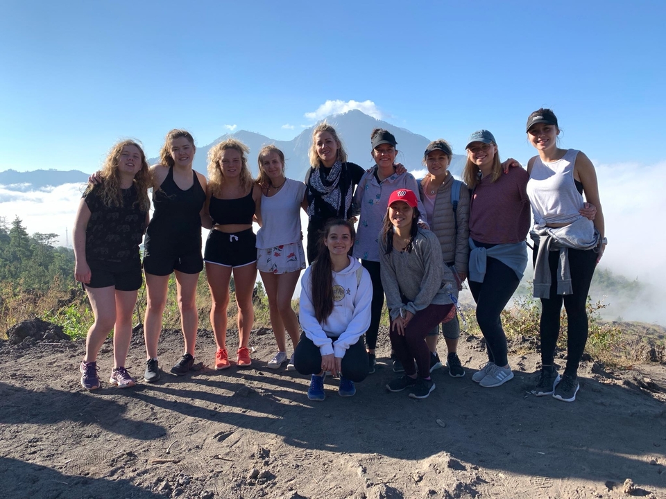 Group of people posing in front of mountains and clouds.
