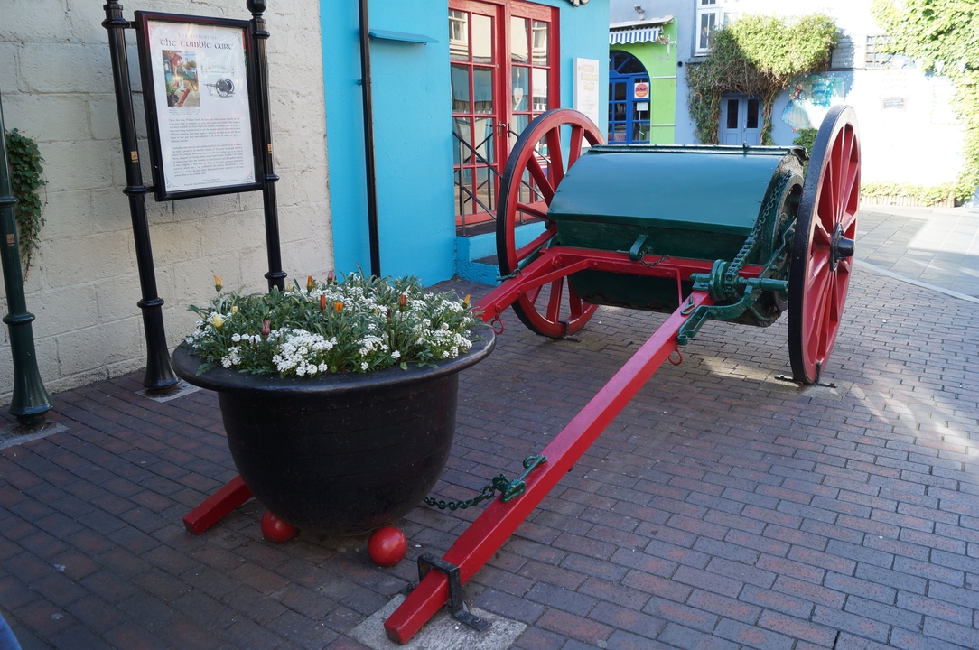 Un chariot de fleurs coloré dans une cour avec un mur lumineux en arrière-plan.