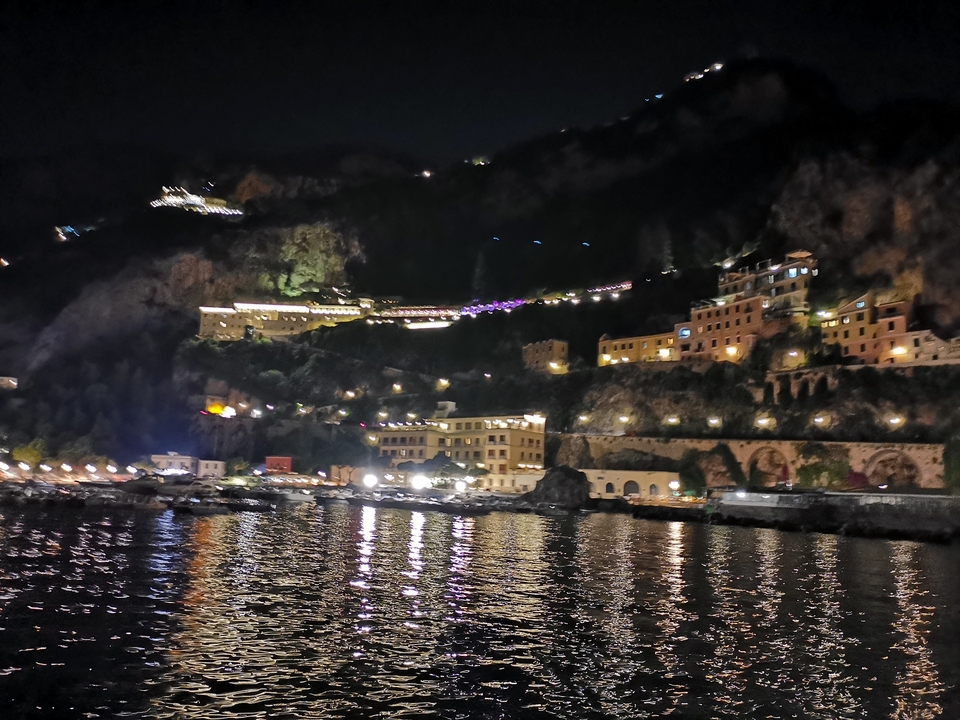 A night view of a coastal town with illuminated buildings.