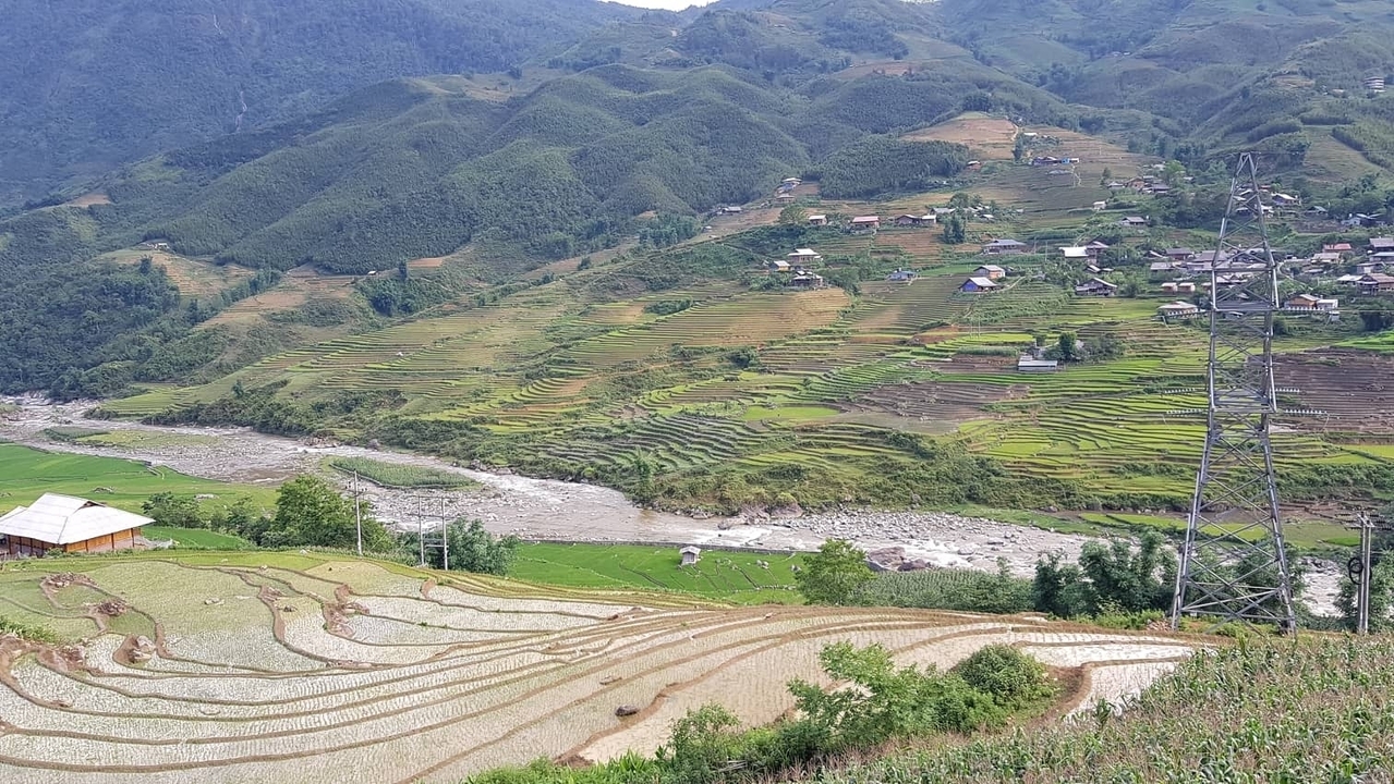 Champs en terrasses dans une vallée avec des montagnes au loin.