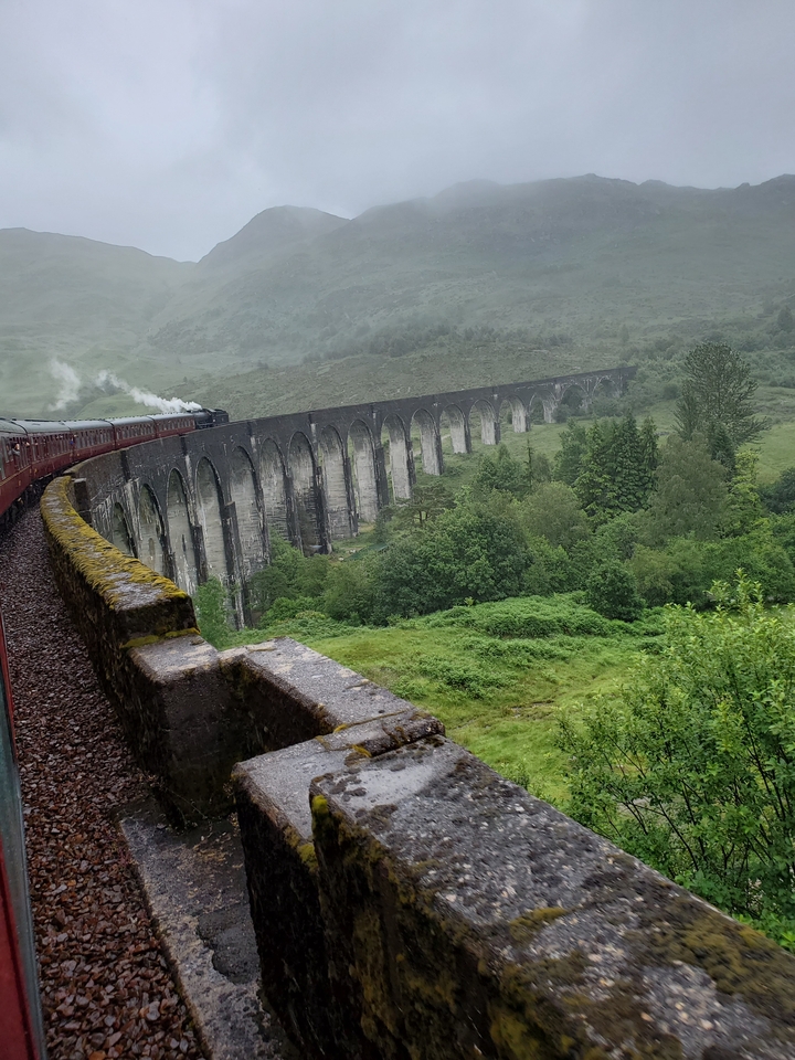 Train crossing over a historic arched railway bridge.