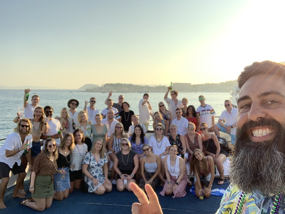 Large group of people on a boat with coastline views.