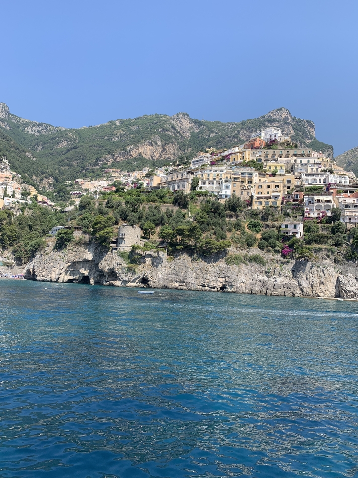 Coastal cliffs with colorful houses and clear blue water.