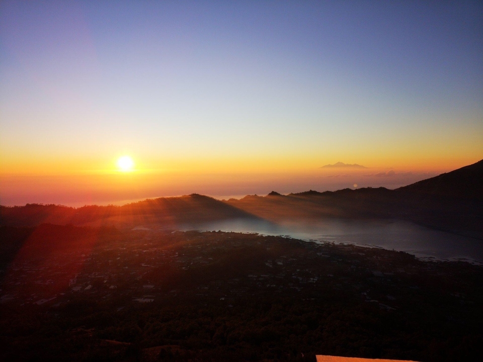 Sunrise over a mountainous landscape and water.