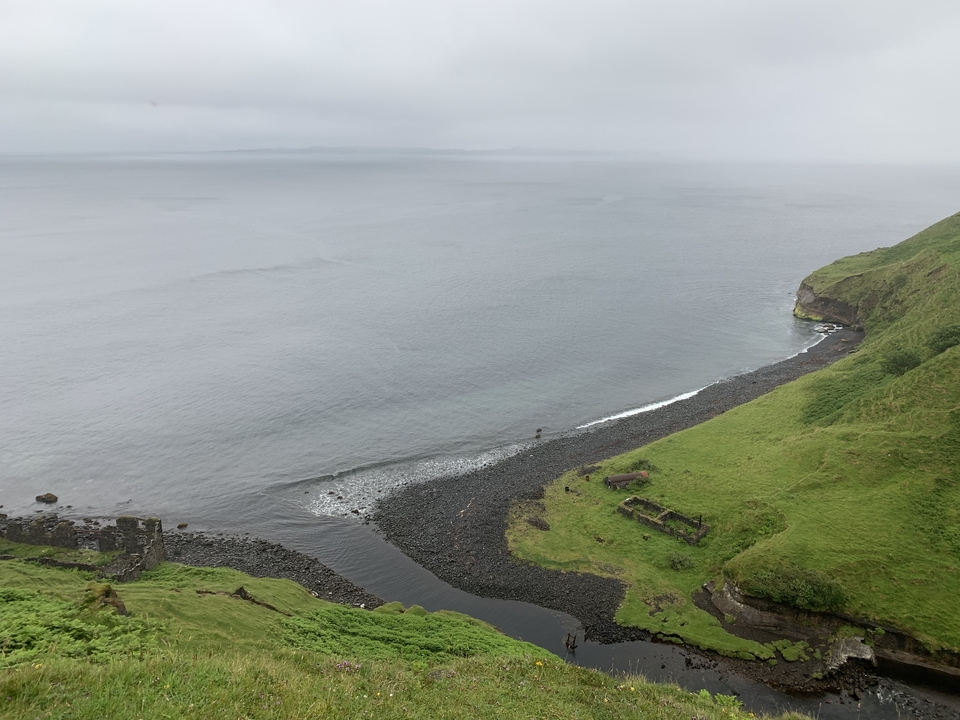 Coastal view with cliffs and grassy fields.