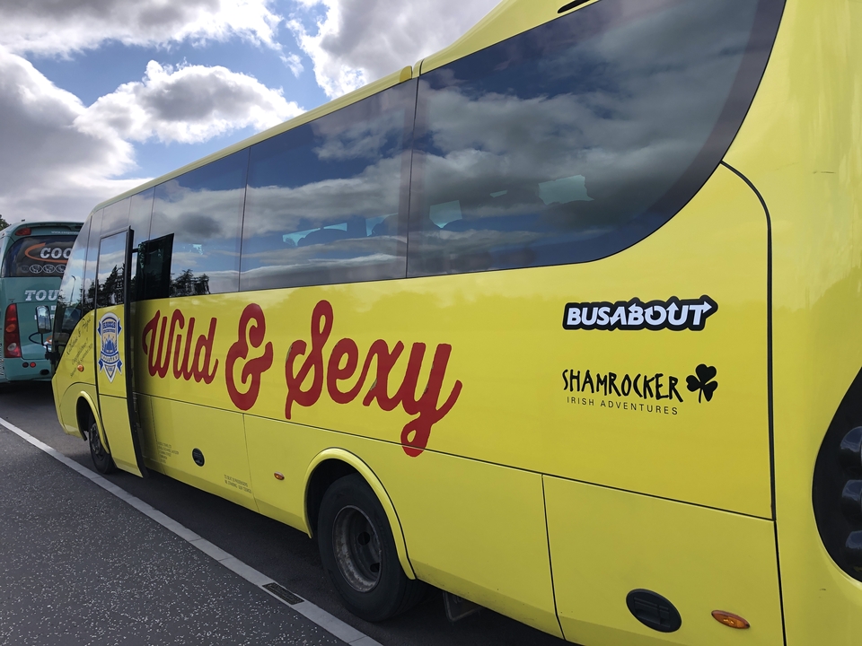Une vue de côté d'un bus touristique jaune avec du texte décoratif sur le côté.