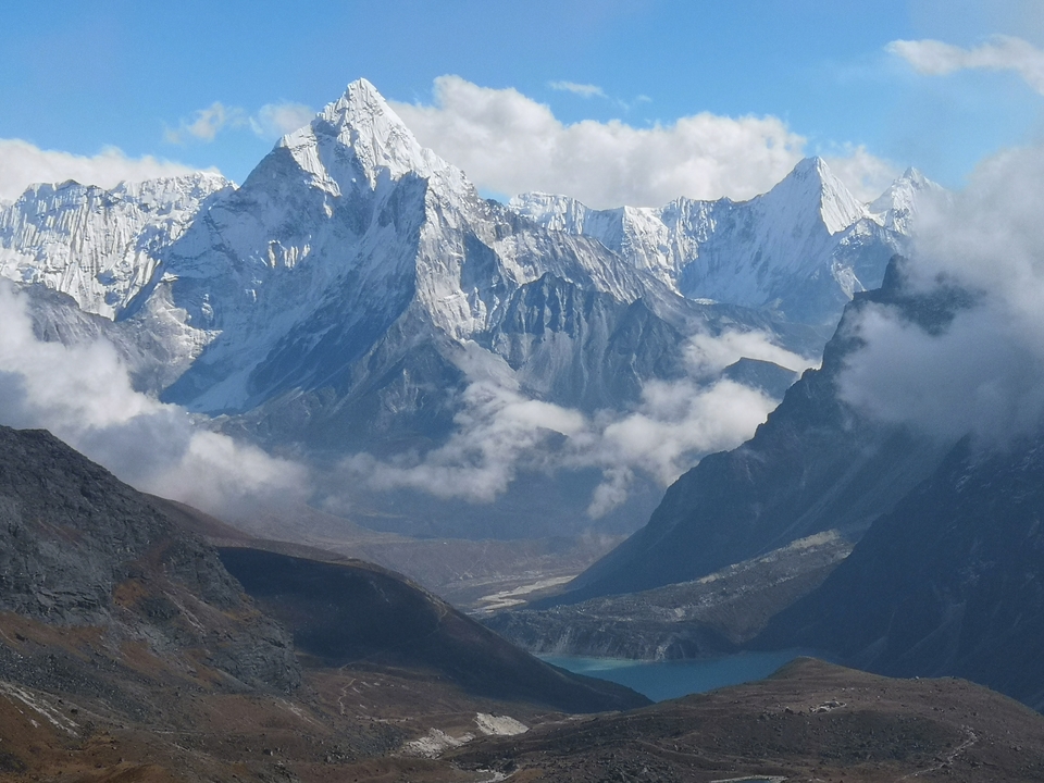 Vue spectaculaire sur une chaîne de montagnes avec des nuages et un lac.