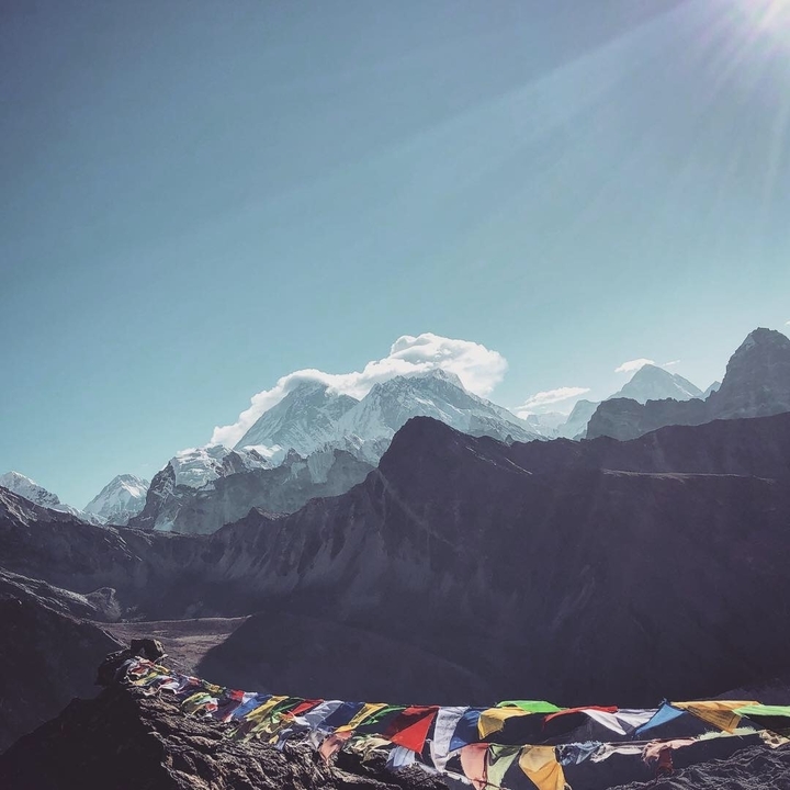 Vue lointaine de sommets montagneux enneigés avec quelques nuages.
