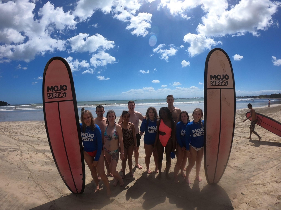 A group of people posing with surfboards on a beach.