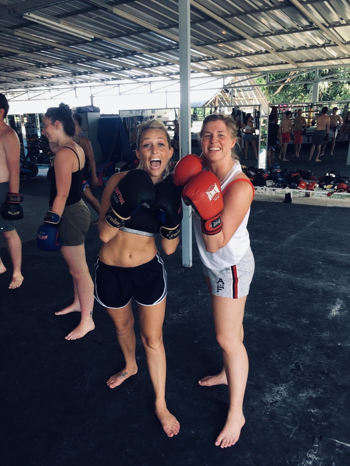 Two women with boxing gloves in a gym.