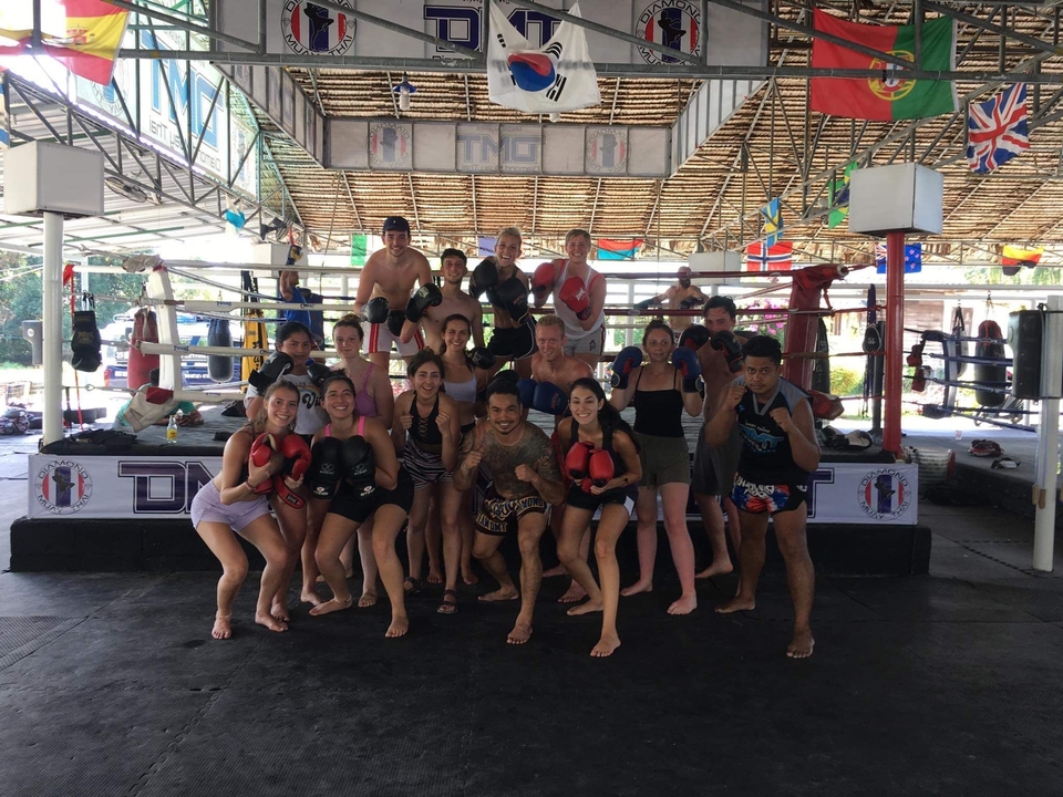 Large group posing inside a boxing gym with boxing gloves.
