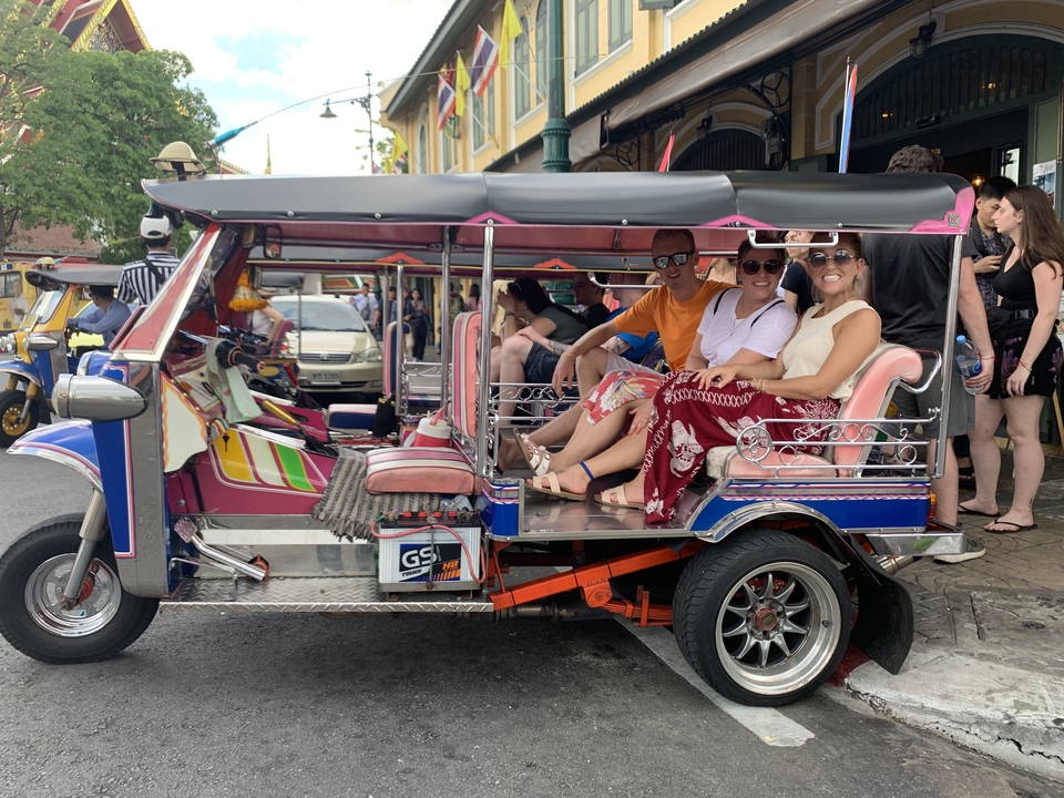 Group of friends sitting in a tuk-tuk on the street.