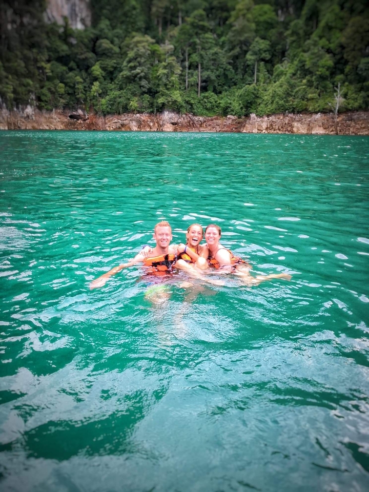 Three people swimming together in a lake.