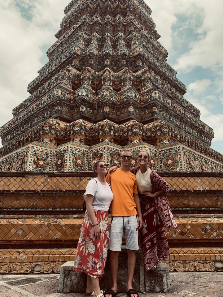 Three people posing in front of an ornately decorated structure.