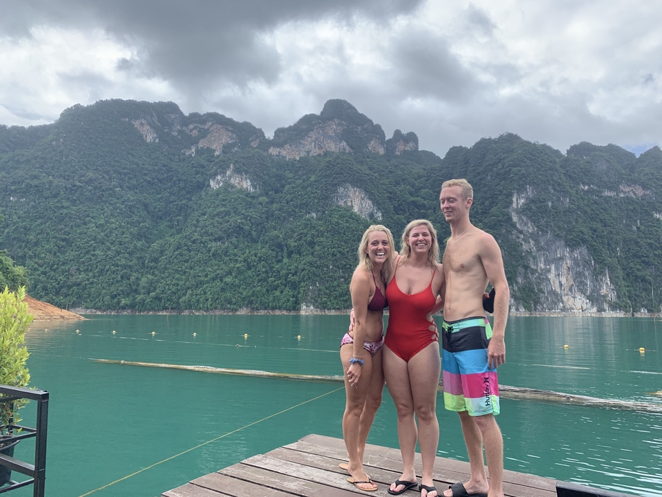 Three people at a scenic lake with mountains in the background.