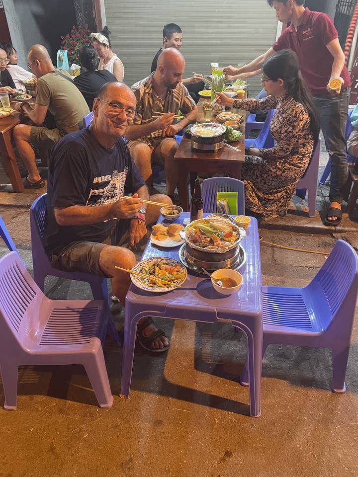 People dining outdoors at a street food stall.