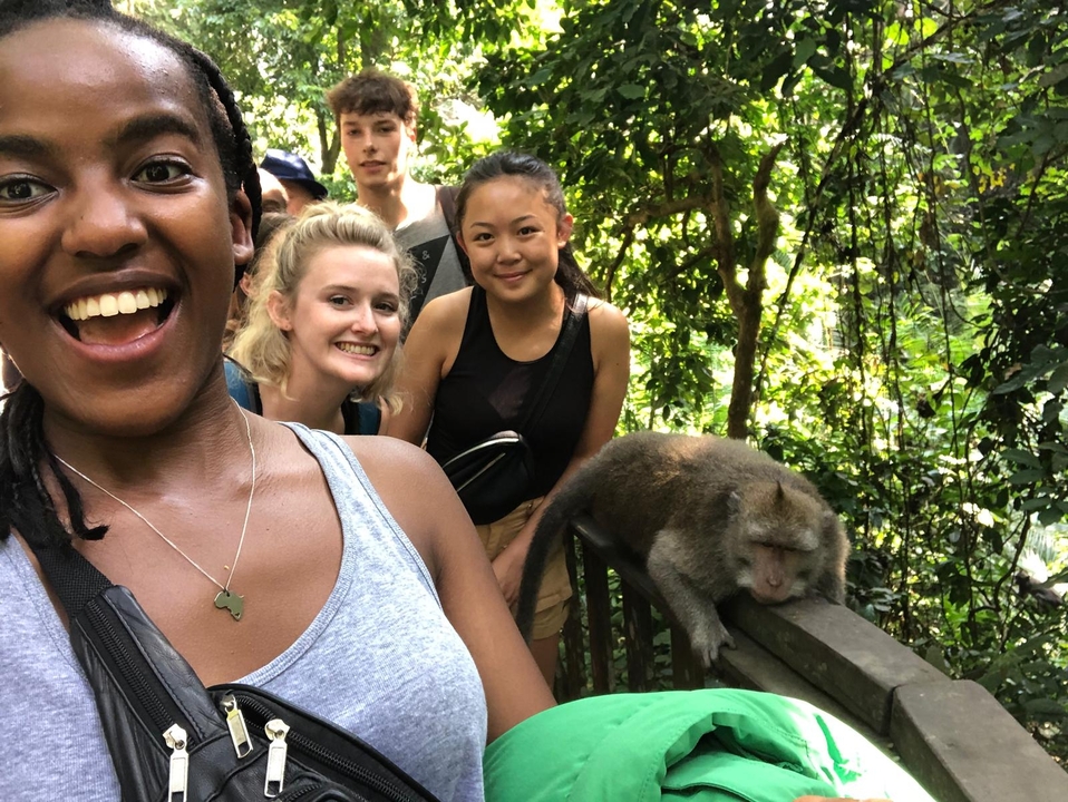 Group of people posing with monkeys outdoors.