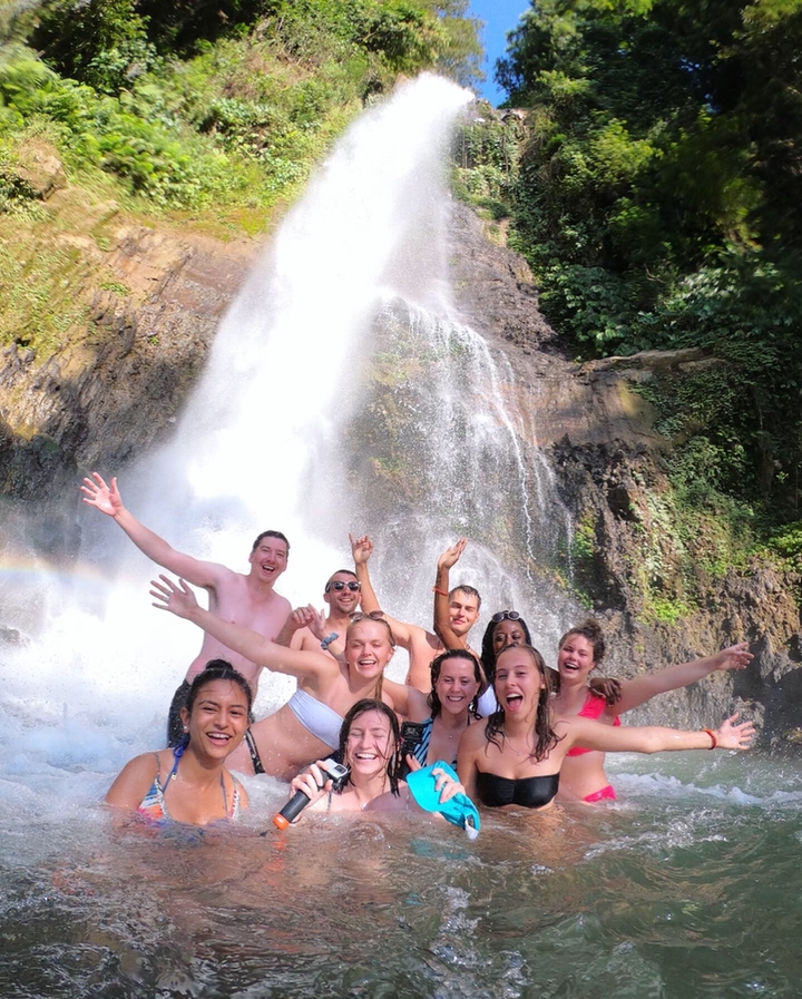 Group of excited people in front of a waterfall.